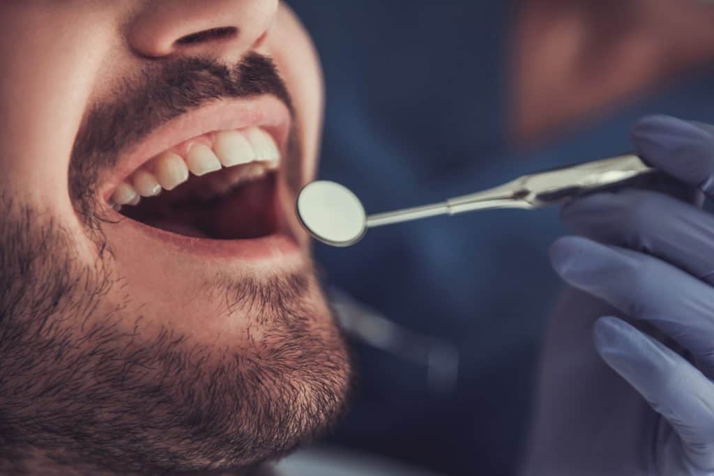 dentist holding a mouth mirror in front of patient's mouth