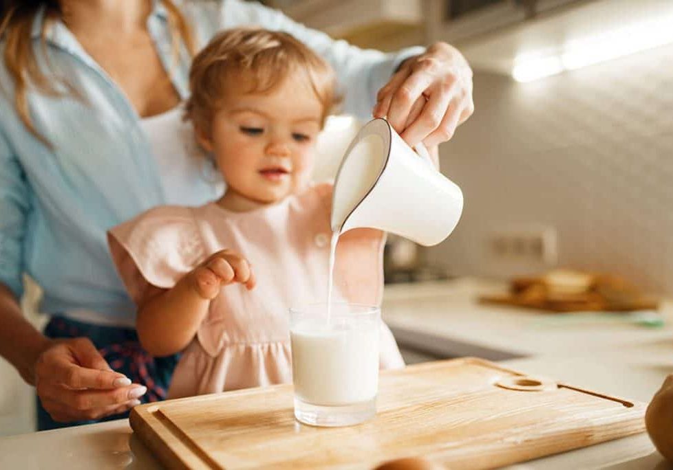 young mother and kid pours milk into a glass
